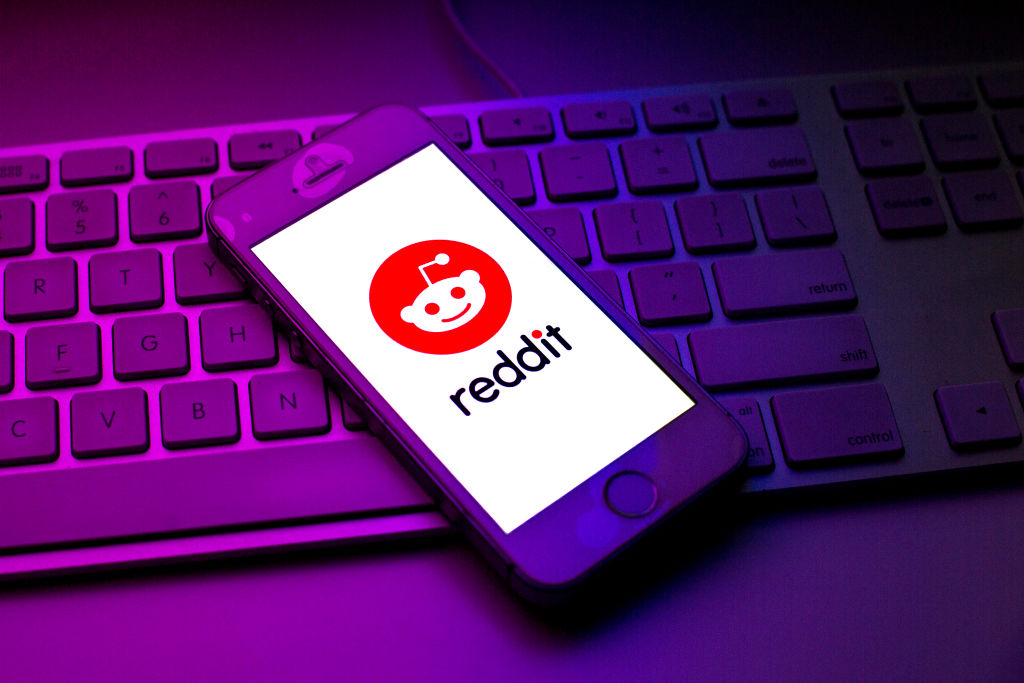 reddit logo on a smartphone sitting on top of a keyboard