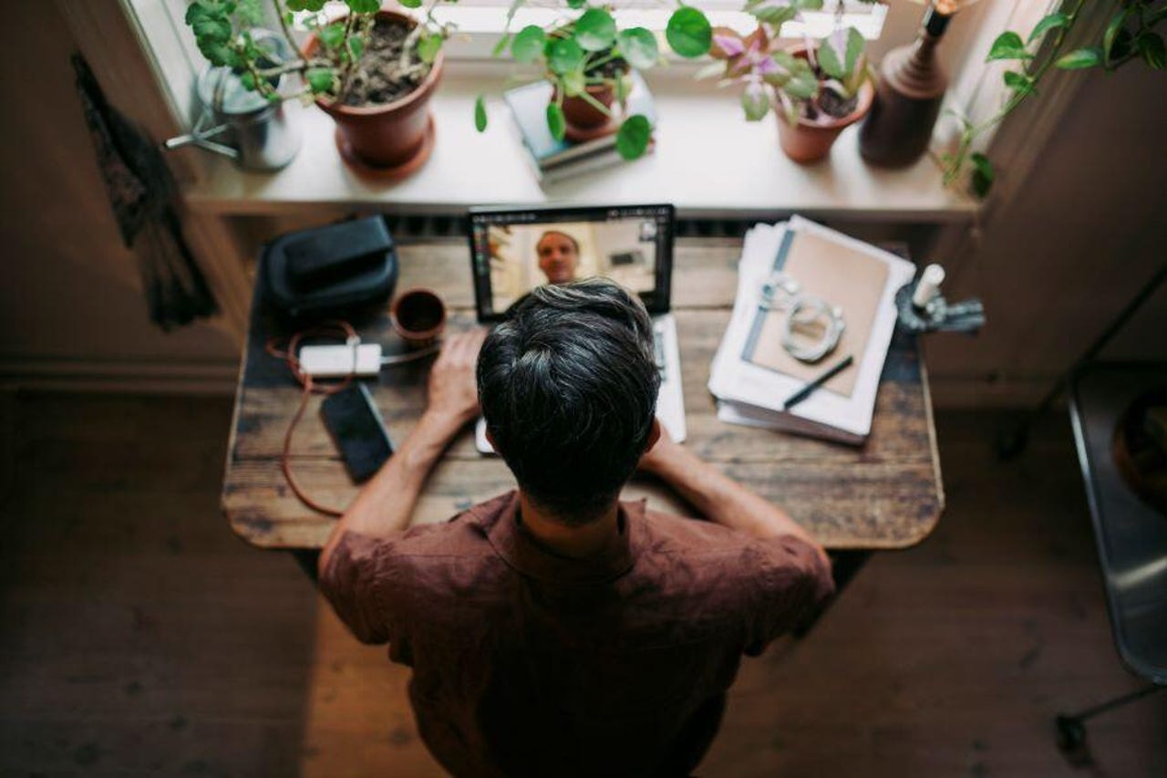 Man working from home at a small desk with plants