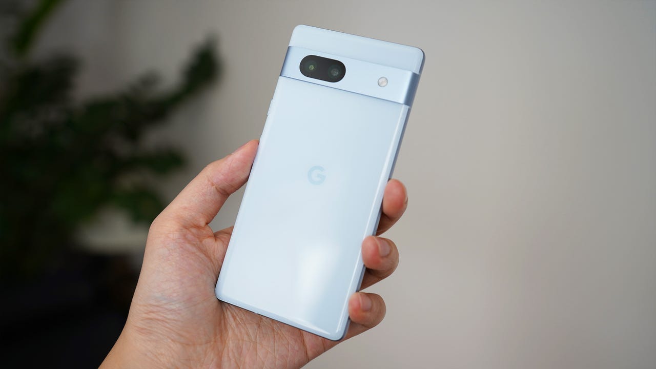 A person holding up the Google Pixel 7a in Sea Blue.