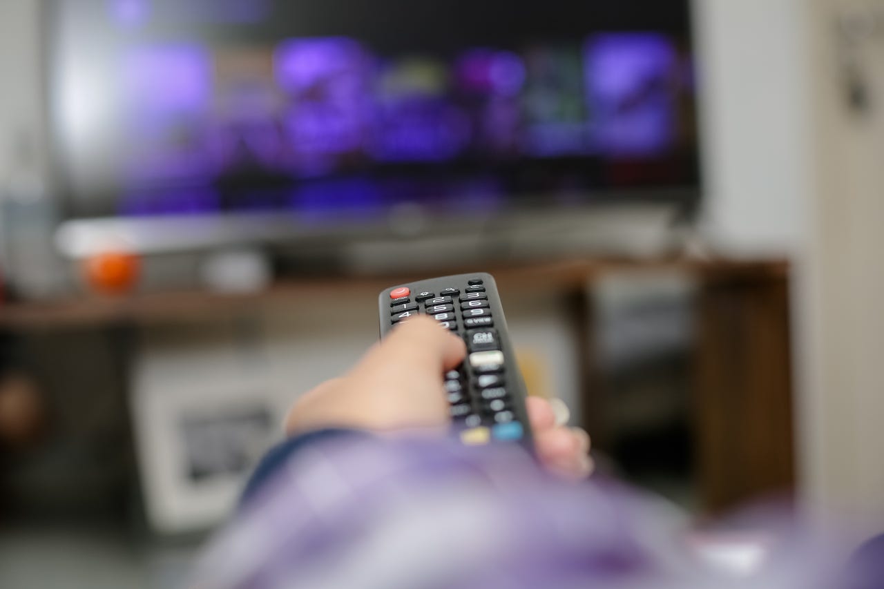 person using remote to control tv