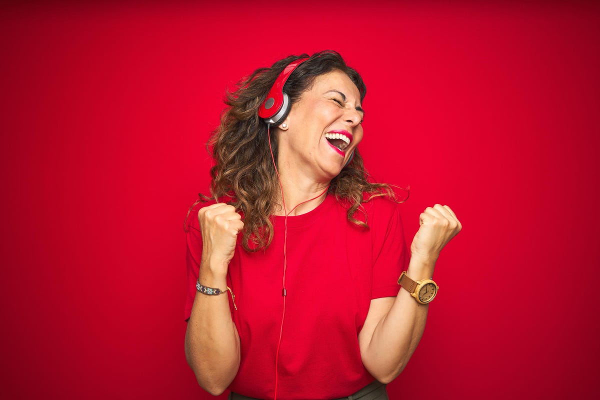 Woman wearing headphones listening to music over red background