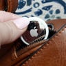Hand putting an AirTag in a purse