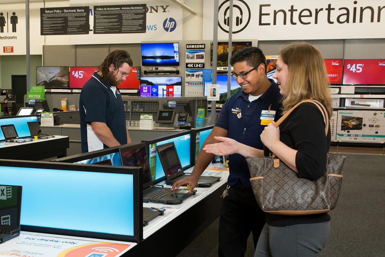 A Walmart employee helps a customer in the electronics section