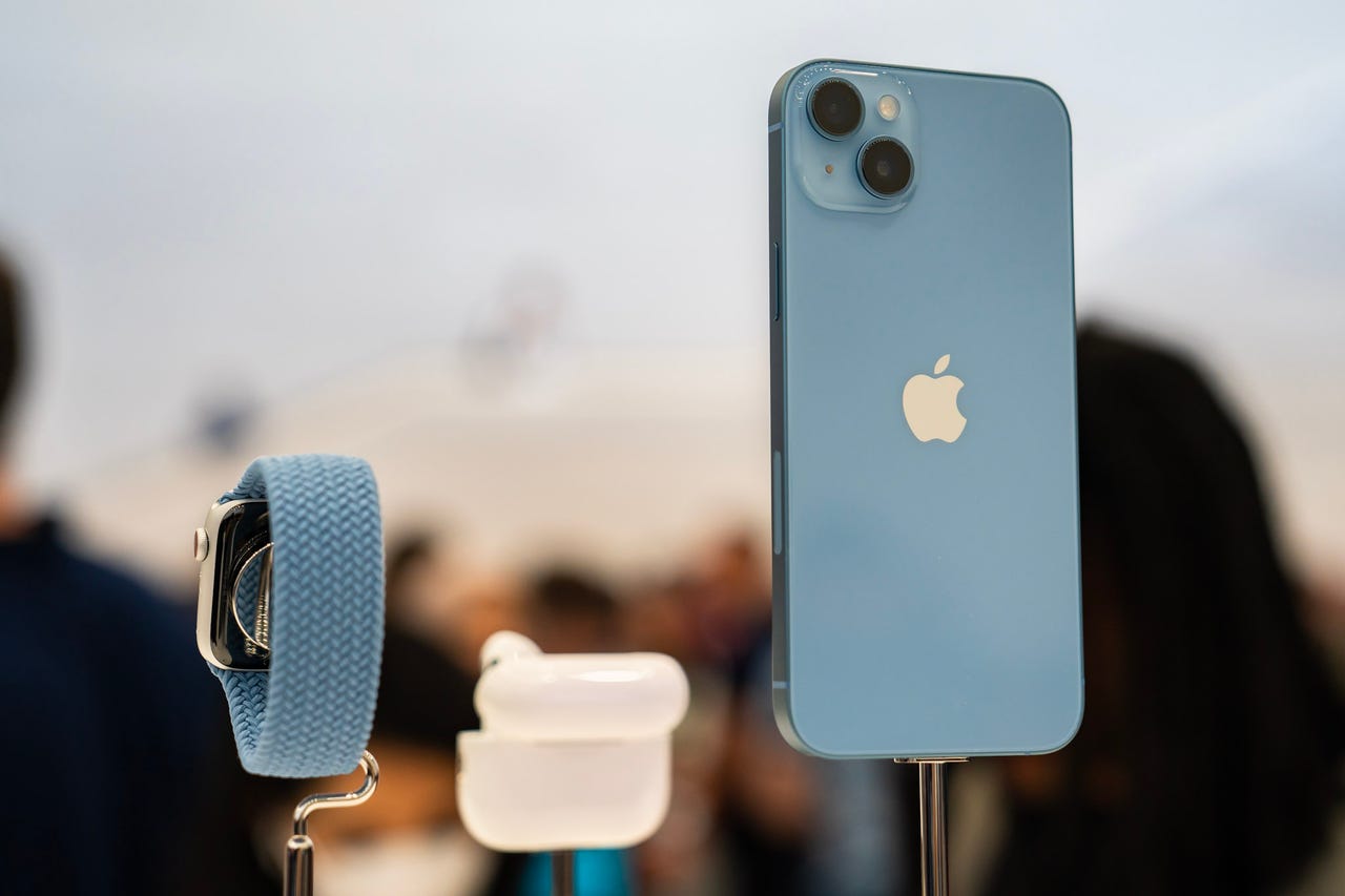 iPhone 14, AirPods Pro (2nd gen), and Apple Watch Series 8 on stands from the back