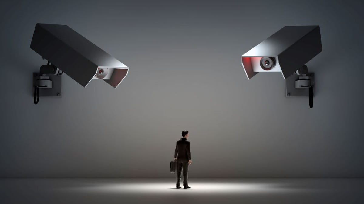 Businessman being watched by large security cameras.