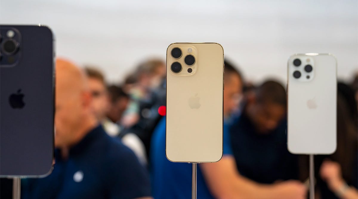 iPhone 14 Pro models on stands in a crowded Apple Store