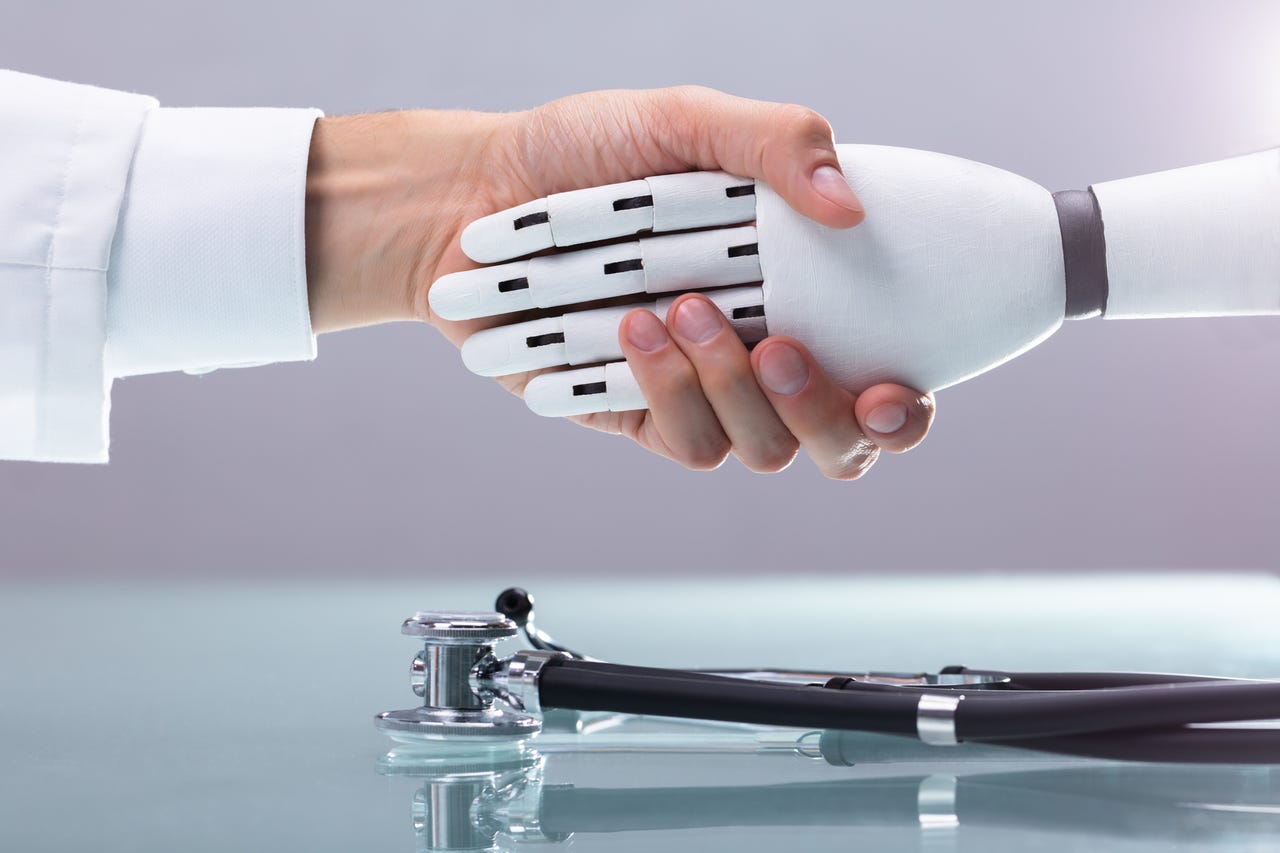 Human shaking hands with robot with stethoscope underneath them