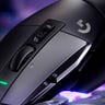 Close-up of a floating Logitech G502 X Lightspeed mouse, pointed downward, in front of an abstract purple background