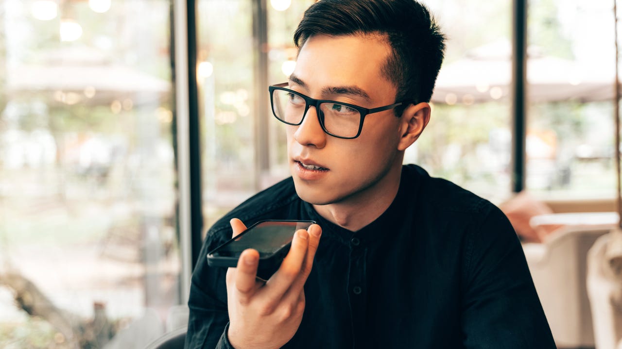 Young man with glasses speaking into his smartphone.
