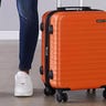 Orange carry-on luggage next to person's legs