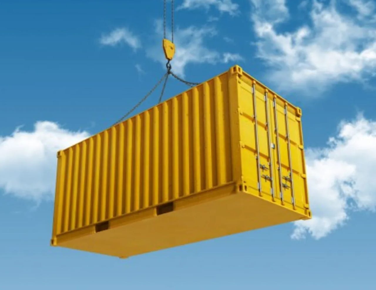 A yellow shipping container being hoisted into the sky
