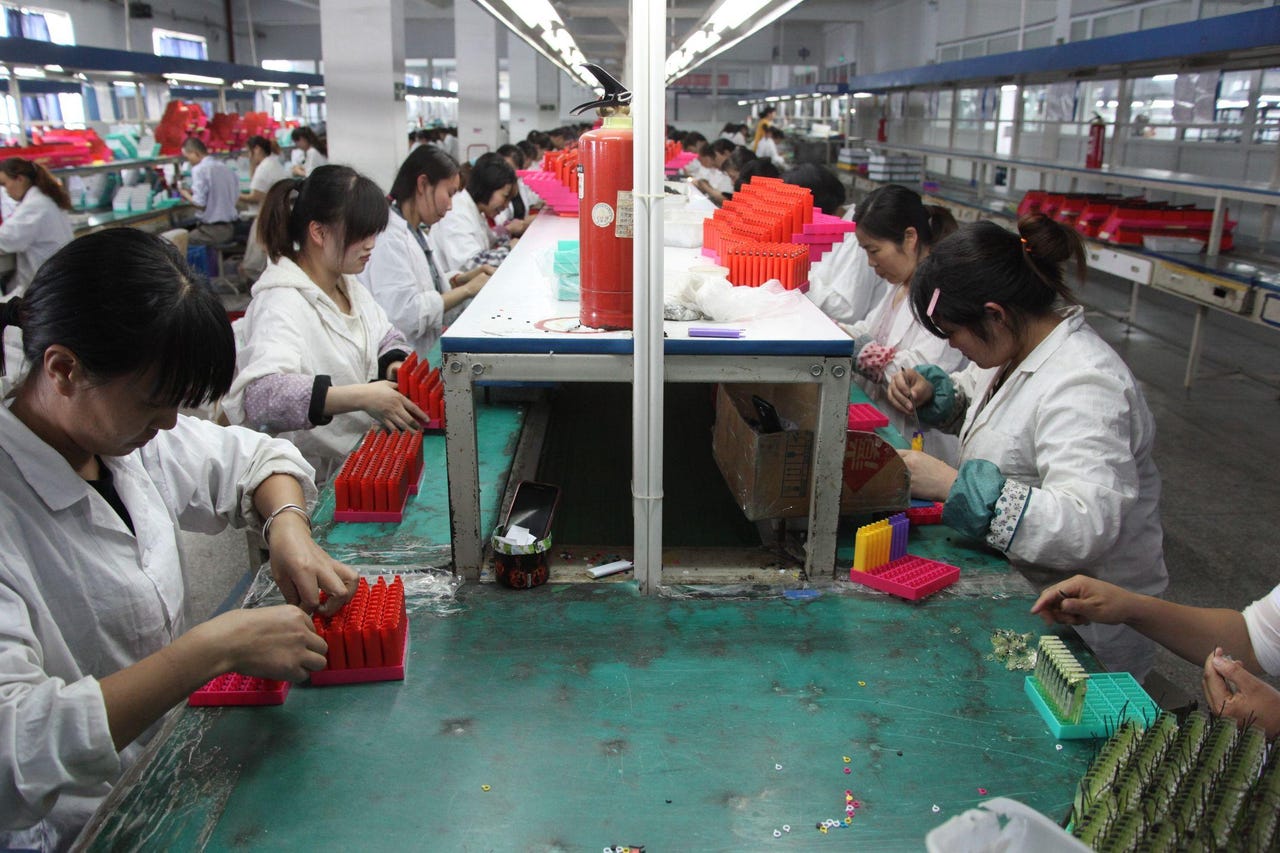 Chinese workers assembling lighters in factory.