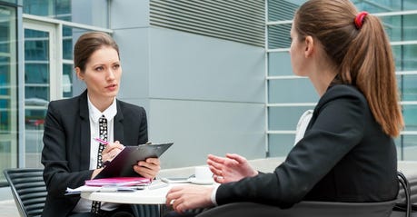 A woman interviews a female job candidate outside.
