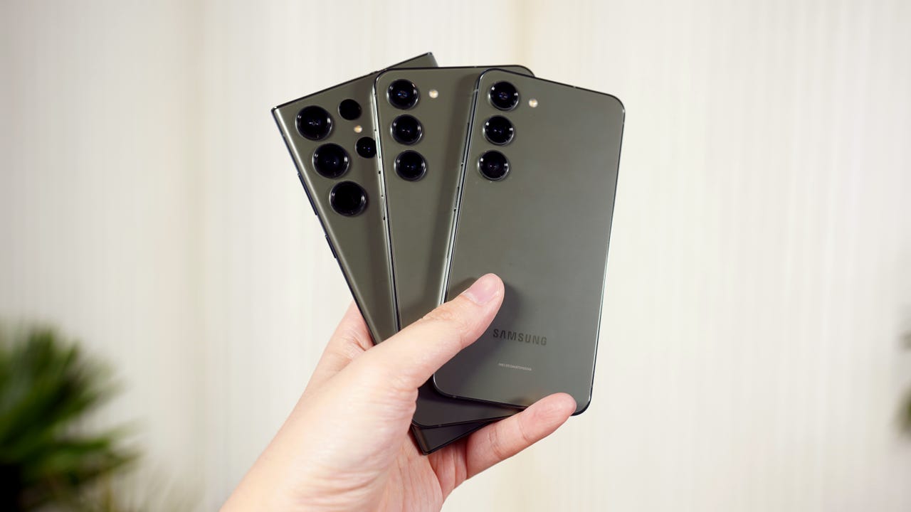 Three Samsung Galaxy S23 phone models fanned like cards in a hand
