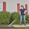 A woman in jeans and a t-shirt using a Craftsman CMEPW1700 pressure washer to clean her sidewalk