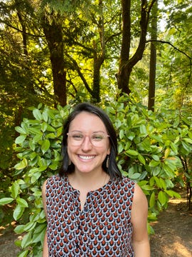 lauren albano, a woman with dark hair and glasses, smiles at the camera.