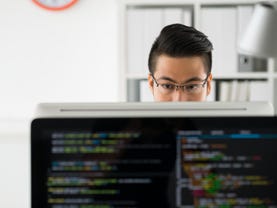 Pensive programmer working on computer in office