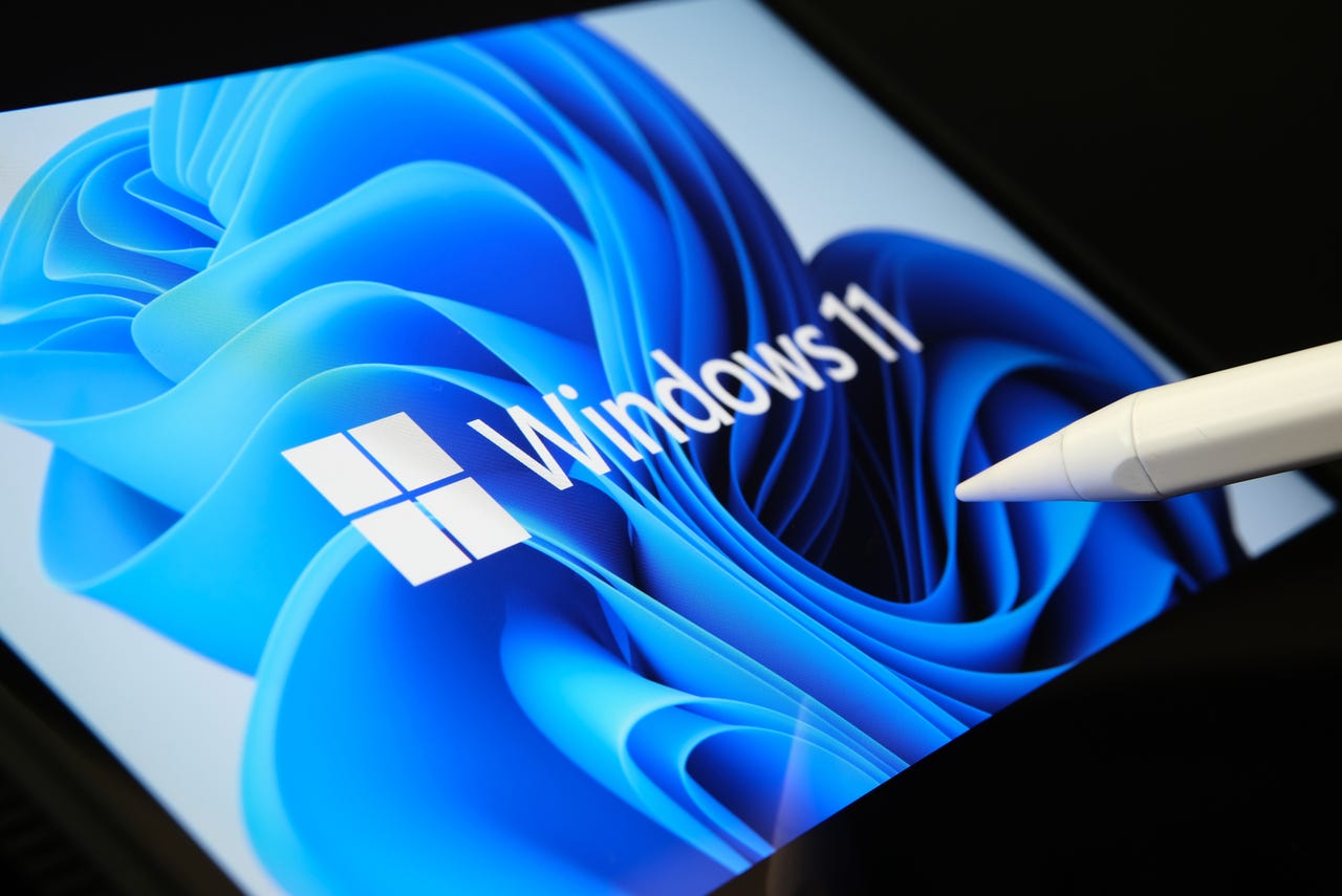 Microsoft Windows 11 operating system logo seen on the screen of tablet and user pointing at it with stylus