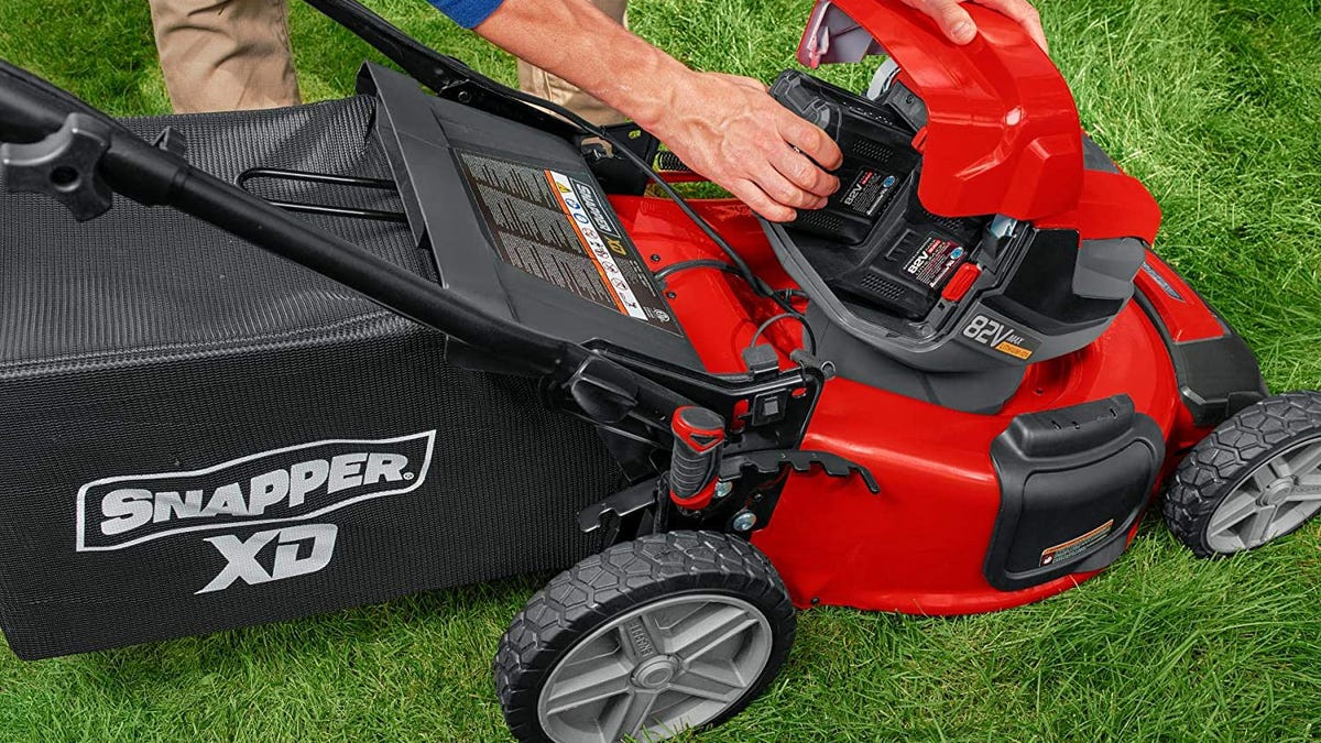 Partial view of someone swapping out batteries in a Snapper push mower.