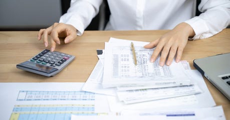 man working at a desk with papers and a calculator