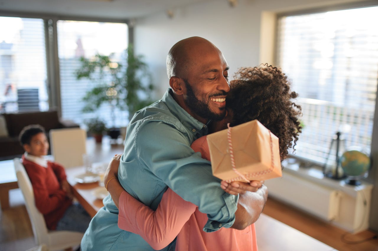Cheerful African American father getting present from his daughter, celebrating. - stock photo