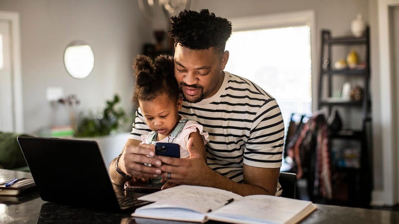 Black Father working from home while holding toddler