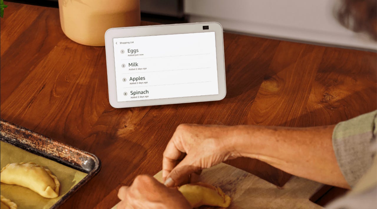 Image of Amazon Echo Show 8 on a wooden table in front of a person cooking and folding pastry dough.