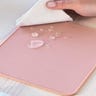 Light pink mouse pad with some water droplets on it