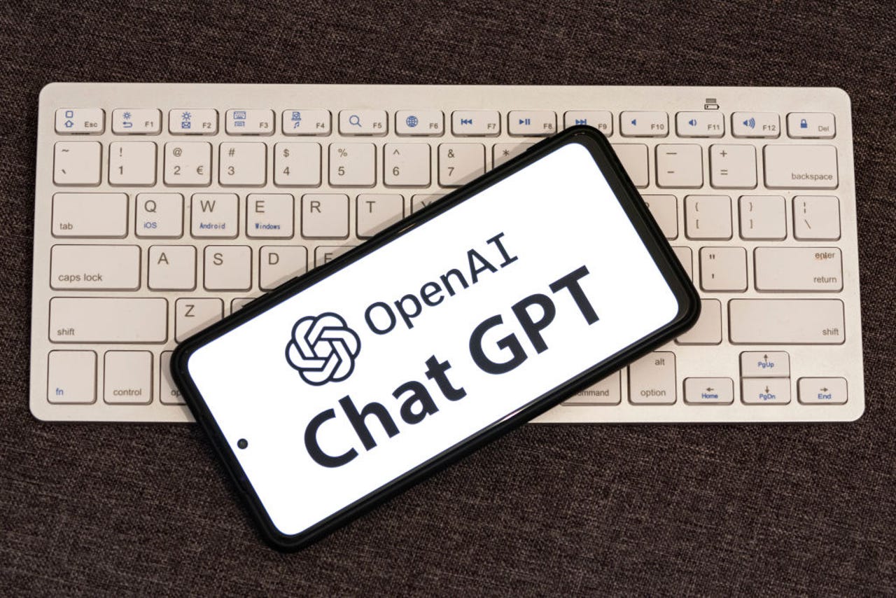 OpenAI and ChatGPT logos on phone that is on a keyboard