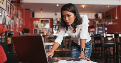 Concerned business woman with medium-length dark hair looking at a laptop
