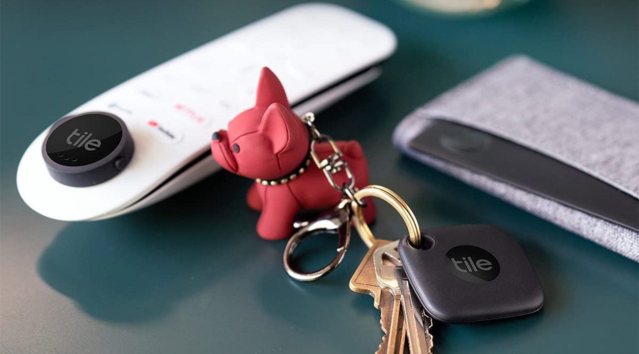 Close-up of a wallet, remote, and key ring with Tile tracking devices attached