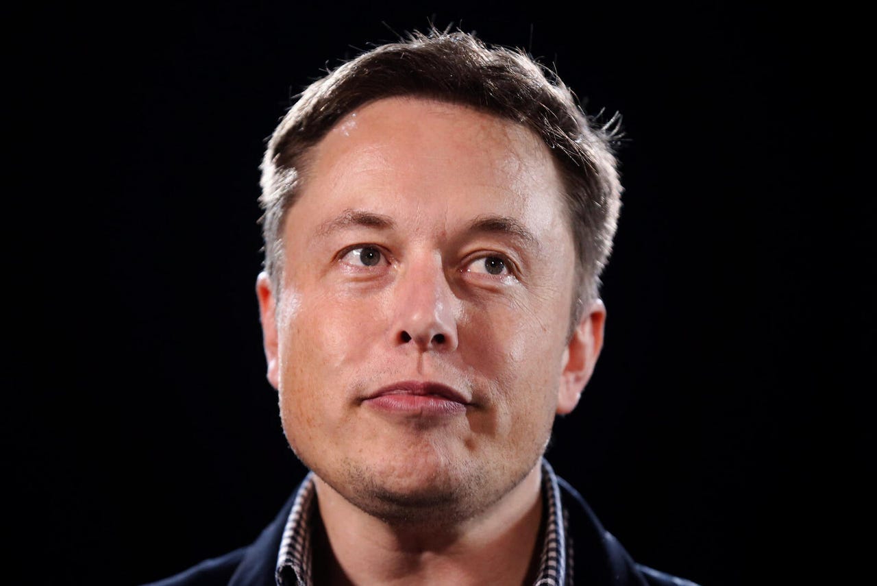 Elon Musk's face lit from behind against a black background
