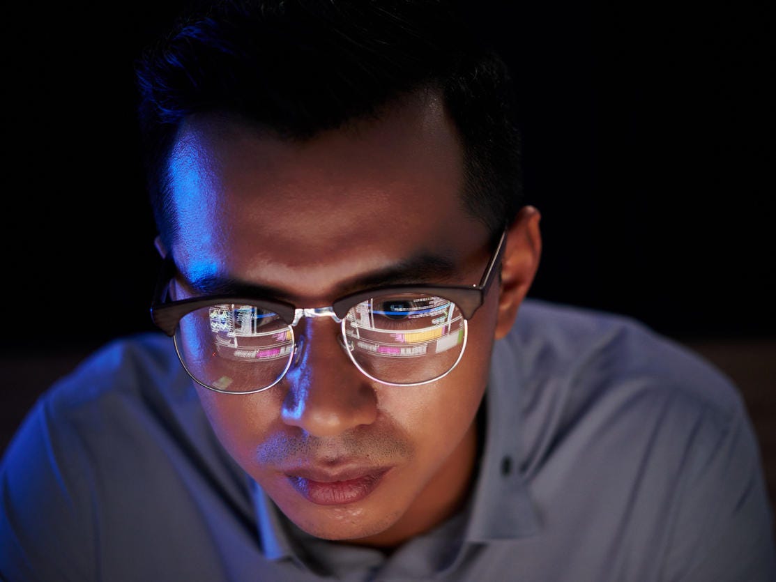 Software developer with programming code reflecting in his glasses