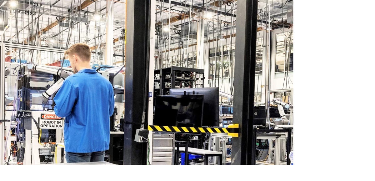 Man in a blue shirt with his back turned, in an Amazon facility