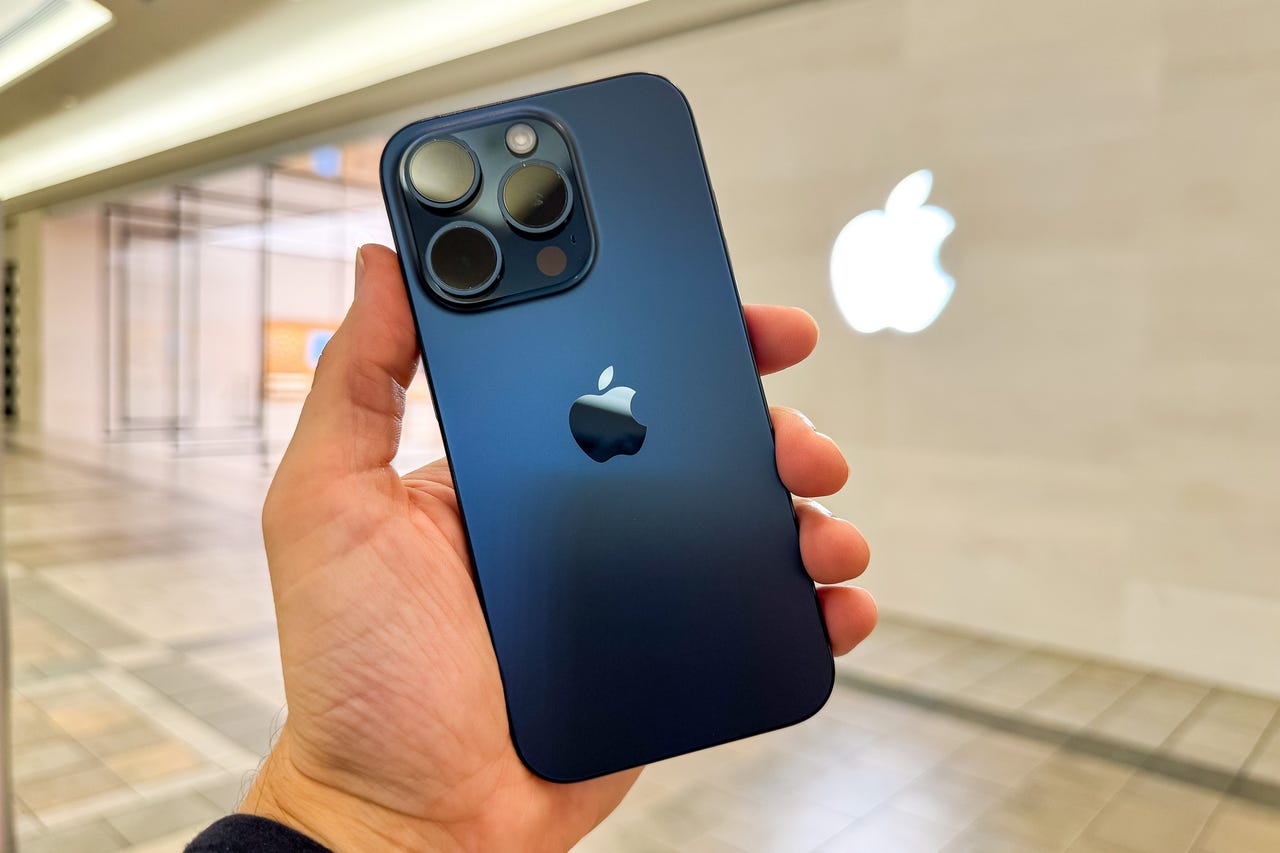iPhone 15 Pro (Blue Titanium) in hand, in front of an Apple Store