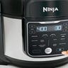 Person pressing a button on a Ninja Foodi pressure cooker