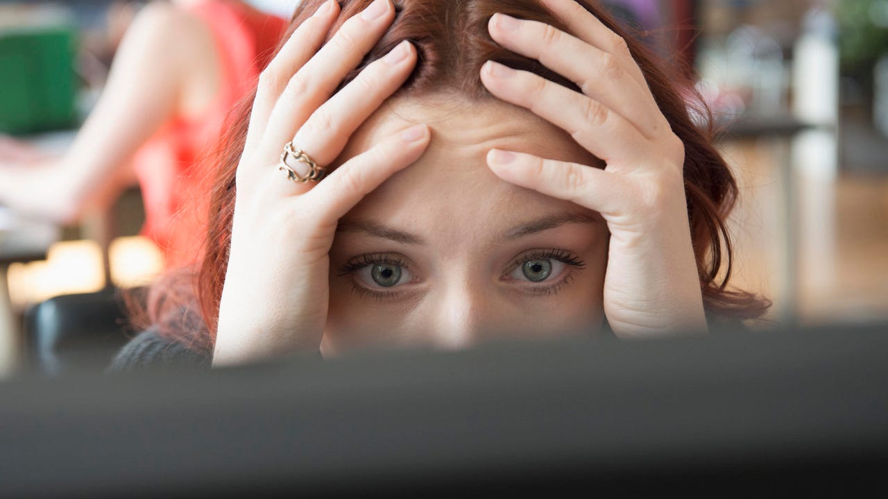 Close up of a frustrated woman at a computer in an office.