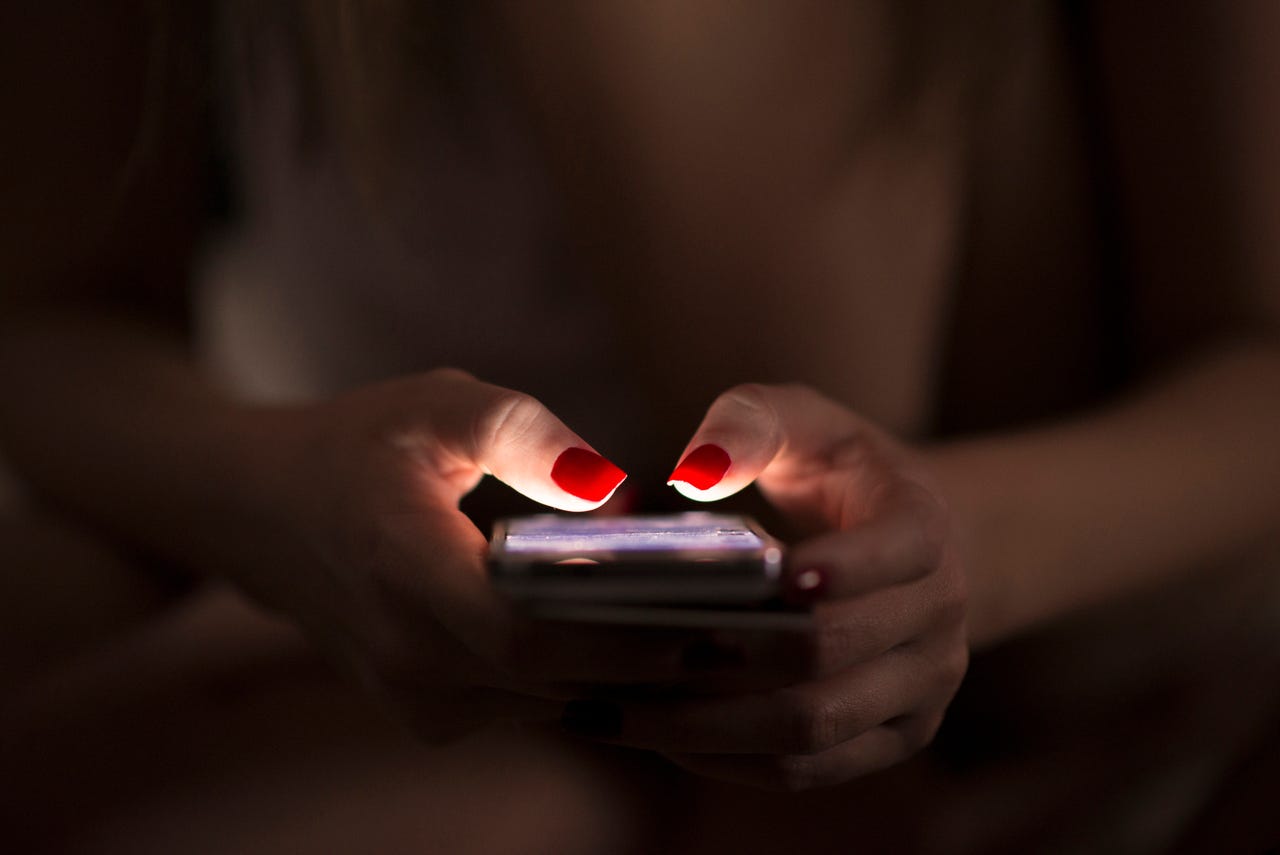 woman holding smartphone in the dark