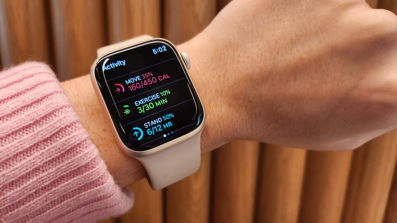 Pink Apple Watch Series 8 on a wrist displaying activity stats.