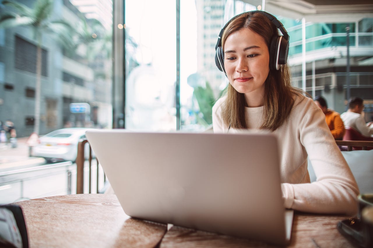Woman with headphones in working on laptop