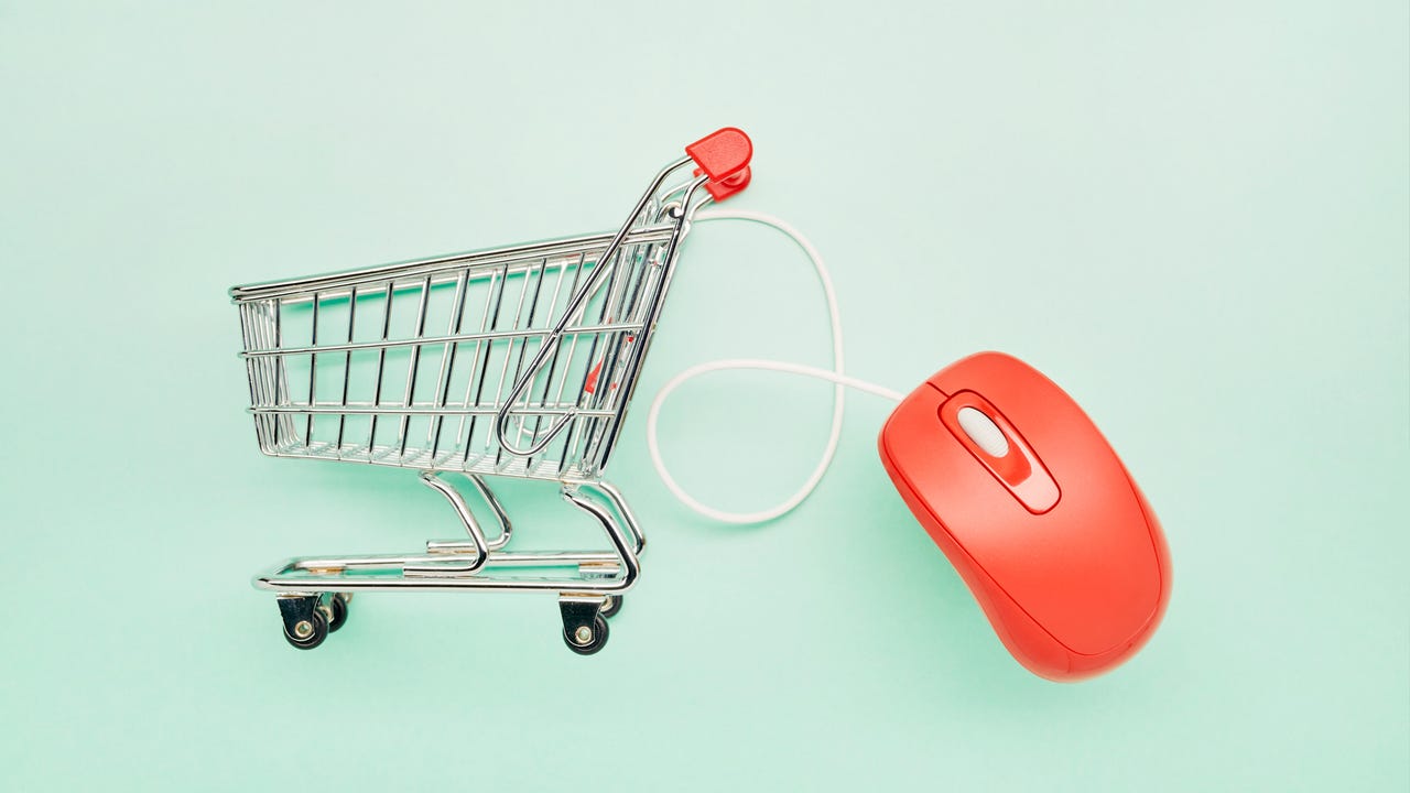 Still life of a small shopping cart and red computer mouse on turquoise background - stock photo