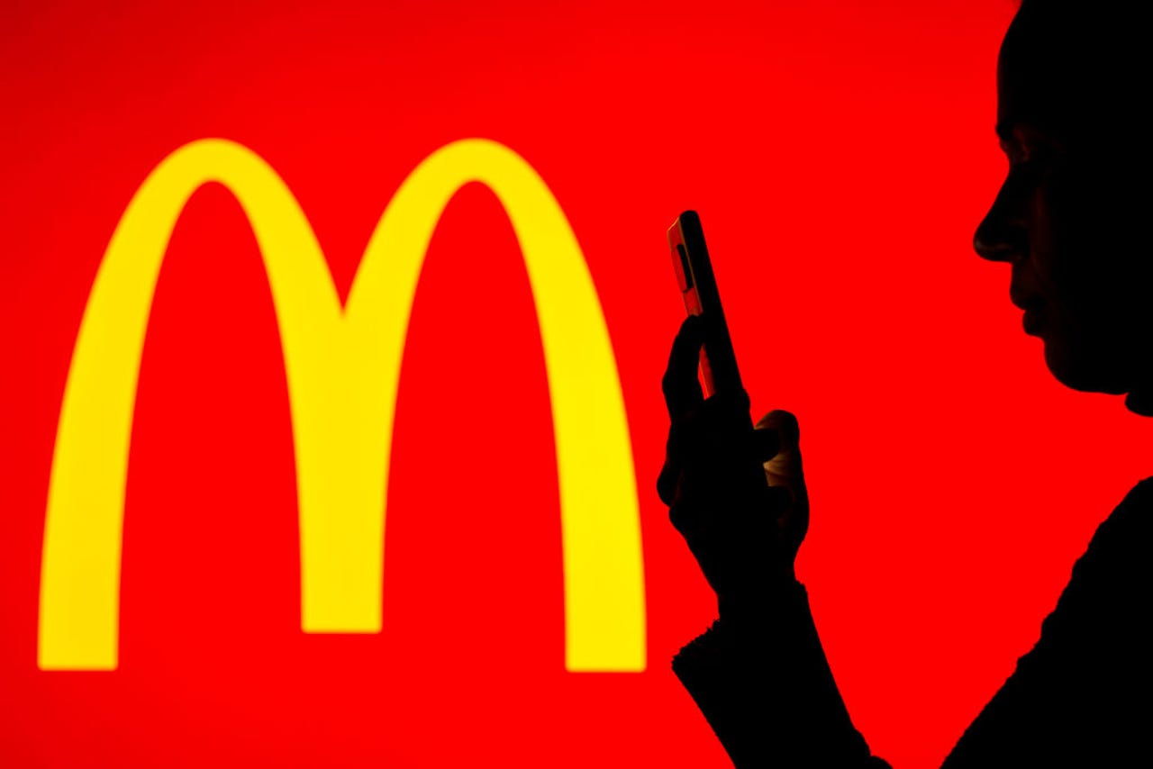 Person holding phone next to McDonald's logo