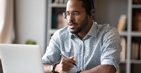 Black man wearing headphones and studying in front of a laptop