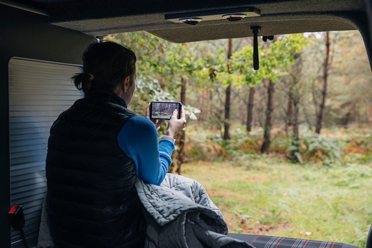 Woman taking picture of woods with smartphone