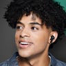 Close-up of a young Black man using a pair of Skullcandy Indy XT earbuds to listen to music