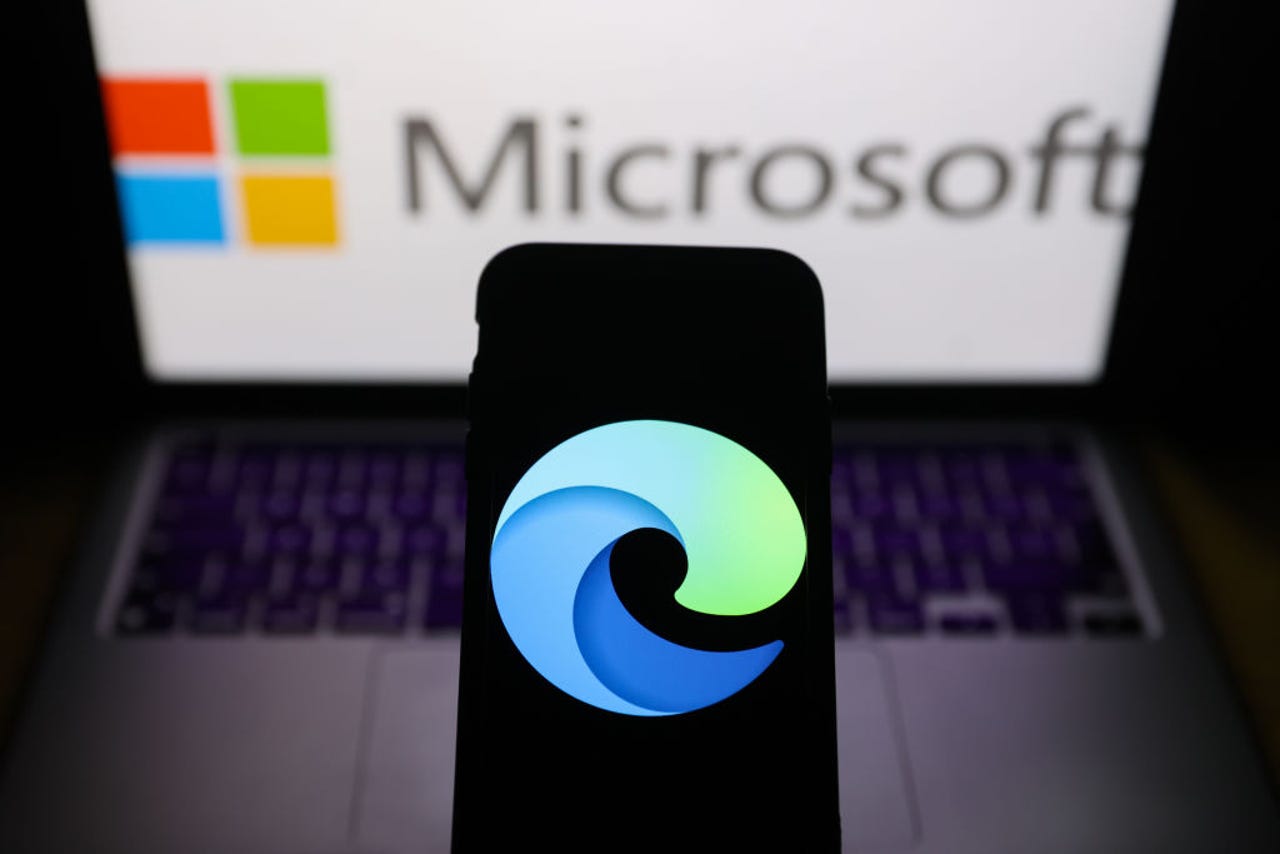 Microsoft Edge logo on phone with laptop in background