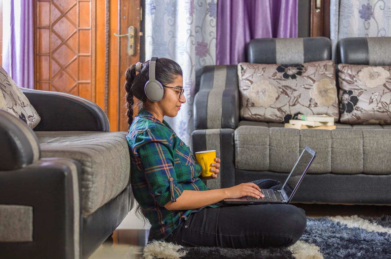 A woman wearing headphones, using a laptop