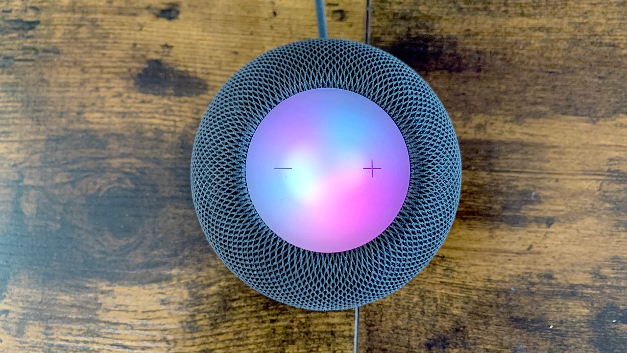 Top view of a HomePod Mini on a wooden table.
