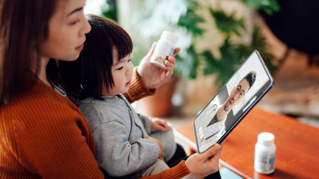 Mother and her toddler daughter talking with doctor on video call with digital tablet. Telehealth and telemedicine service. Healthcare and technology concept.