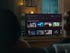 A blurry, from-behind view of a man and woman on a couch, browsing through a list of movies on their TCL 4-Series.